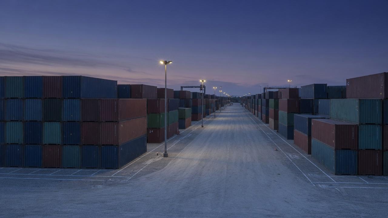 An orderly shipping container depot at dusk